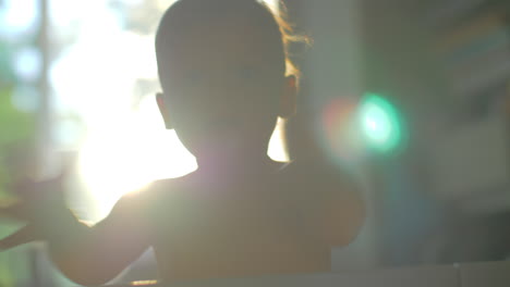 little child clapping hands view against the sunlight at home