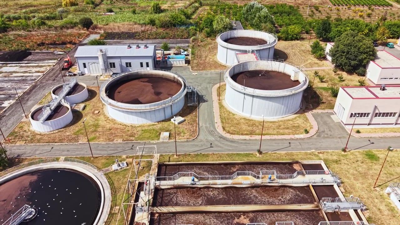 Wastewater treatment plant in operation with several circular tanks and adjacent buildings