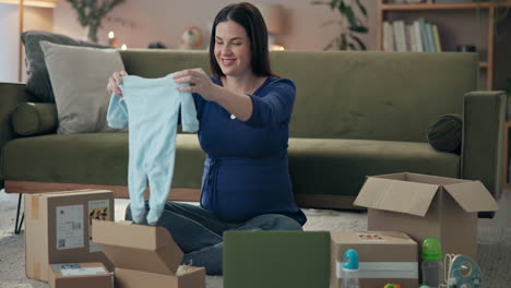 pregnant woman unpacking baby clothes from online delivery