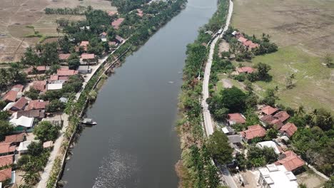 aerial view of a river running through a village and rice paddies