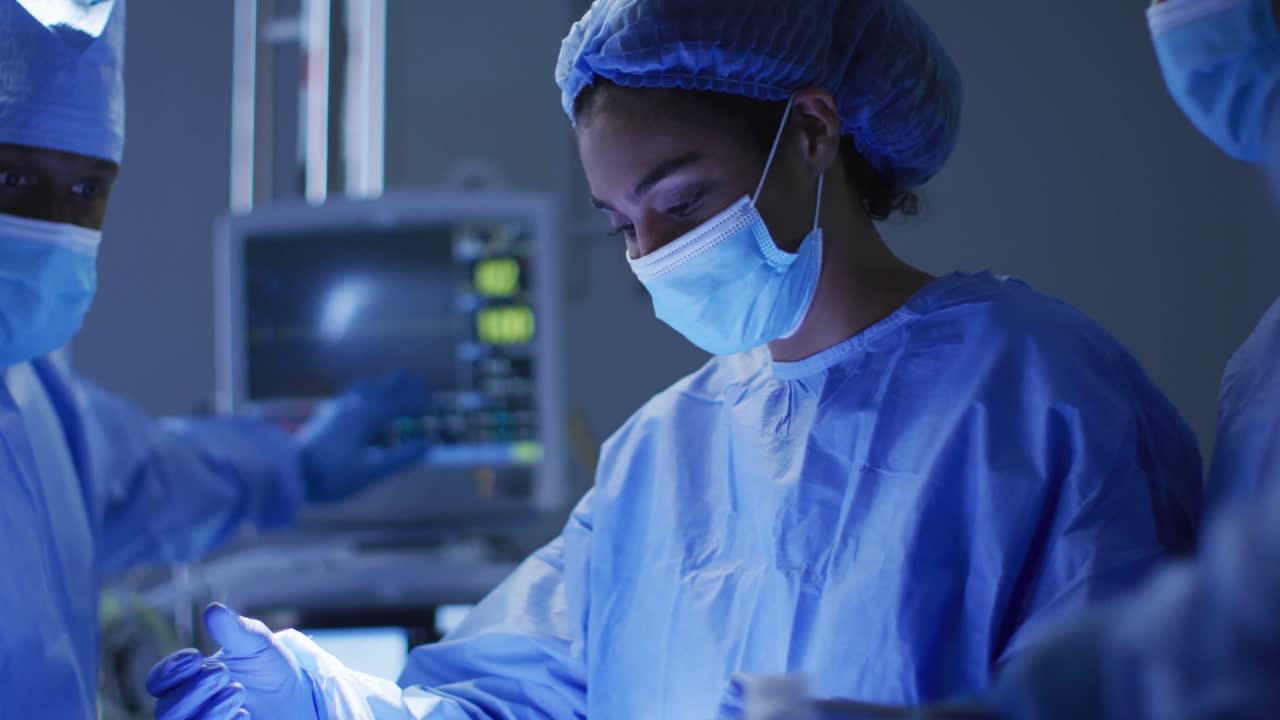Mixed race surgeons wearing protective clothing performing surgery in operating theatre