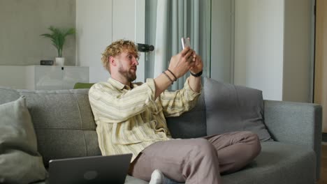 hombre usando teléfono inteligente en el sofá
