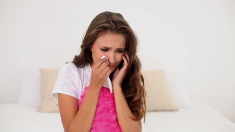 Young-woman-being-dumped-over-the-phone-on-her-bed-holding-a-heart-cushion