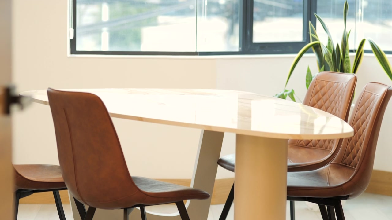 The shot begins with the ring-shaped pendant lamp and descends gently to reveal a meeting table