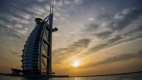 majestic silhouette of burj al arab jumeirah against vibrant sunset sky, reflecting in calm waters of persian gulf, dubai, uae, showcasing iconic architecture and serene beauty