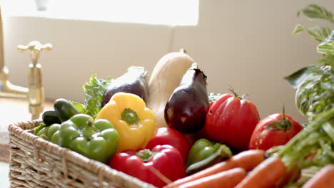 fresh vegetables in basket including carrots, tomatoes, and bell peppers at kitchen, at home