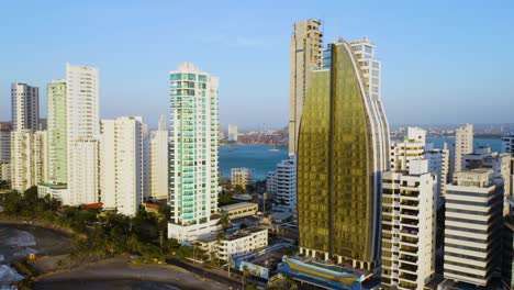 orbiting aerial shot of modern cartagena skyline with ocean background at sunset