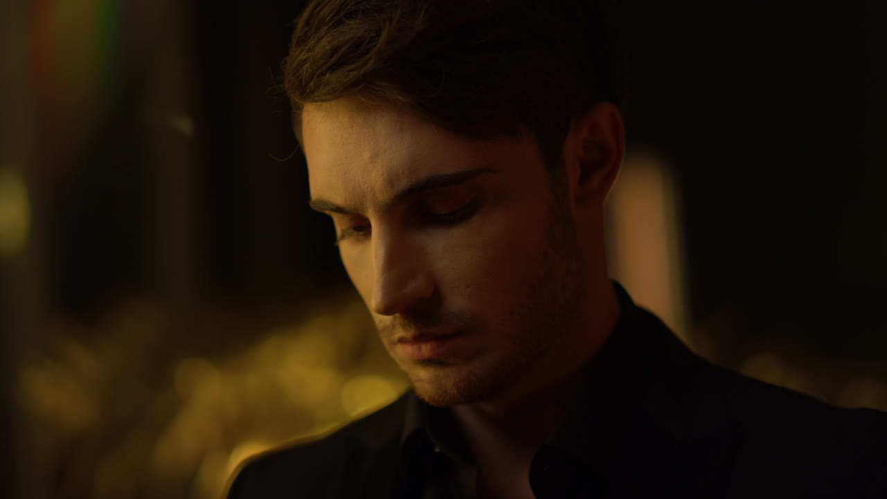 멋진 최고 매니저가 실내에서 카메라를 쳐다보고 있다. 어두운 방에 있는 사려 깊은 남자