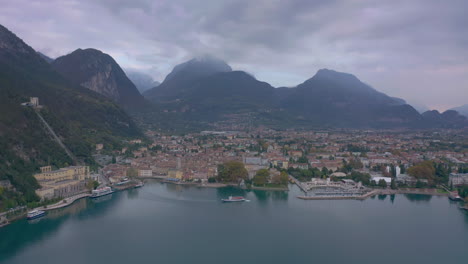 Luftaufnahme-Aus-Dem-Rechten-Schwenk-Nach-Einem-Passagierboot,-Das-Aus-Den-Docks-Von-Riva-Del-Garda-Herausfährt