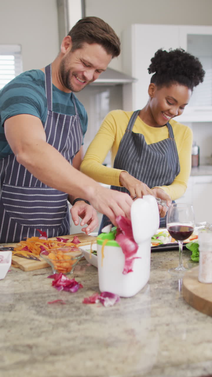 video vertical de una pareja feliz y diversa preparando comida en la cocina