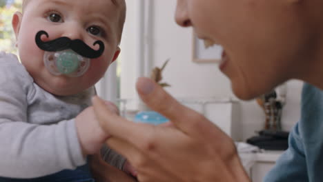 funny baby with moustache pacifier happy mother having fun with toddler at home enjoying silly humor with child sucking on dummy