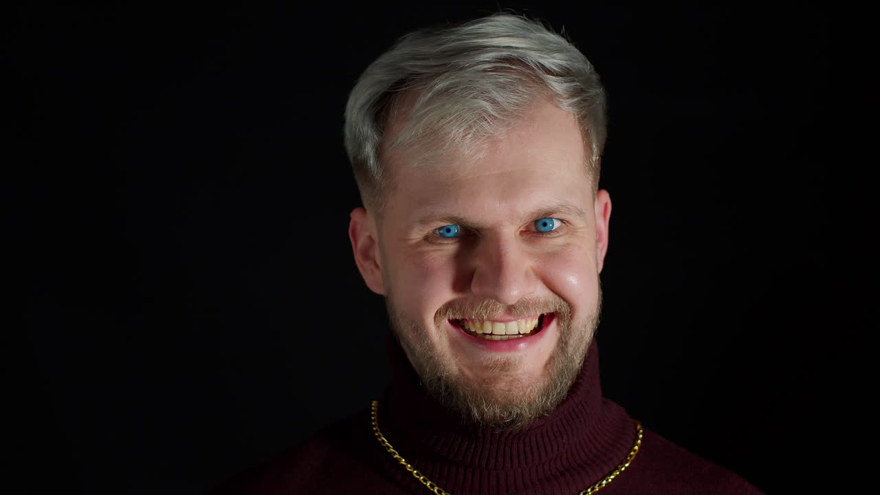 Stylish smiling man with blue eyes looking at camera, charming smile, winking blinking eye, flirting