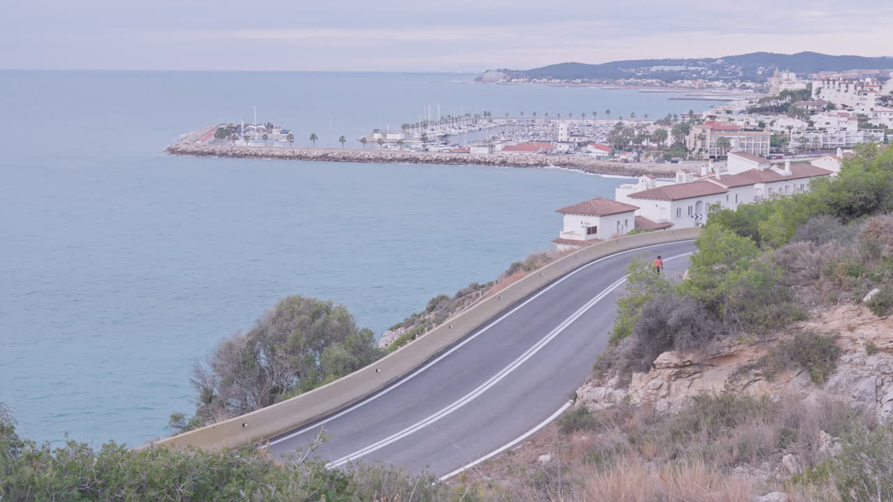 한 명의 자전거 타는 사람이 해안 마을을 향해 구불구불한 길을 따라 이동합니다