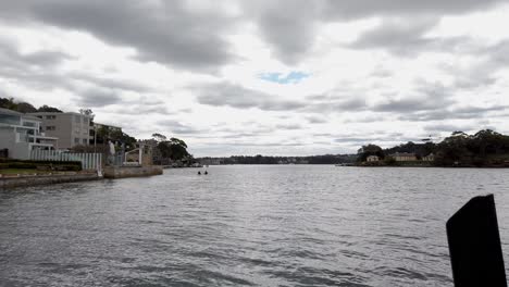 Dos-Kayakistas-Remando-En-El-Agua-De-La-Bahía-En-Balmain-East,-Sydney-New-South-Wales-En-Un-Día-Nublado