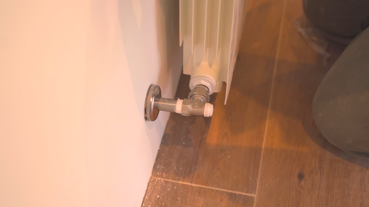 Nærbillede af mand, der justerer radiatormøtrik med en tang indendørs derhjemme