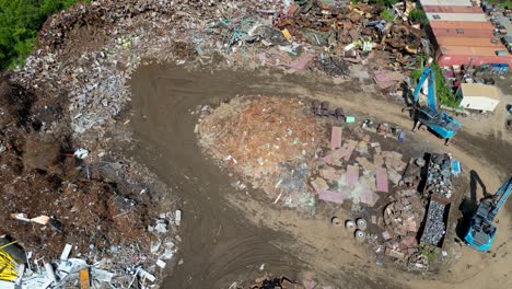 high-angle-pushing-drone-view-of-scrapyard-on-a-bright-sunny-day