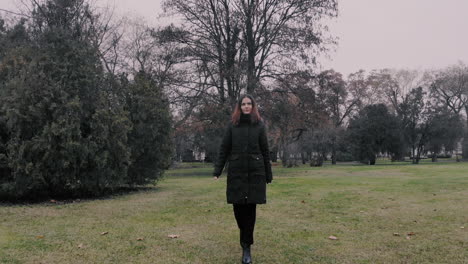 smiling confident woman walking towards the camera in a park on the green grass wearing black