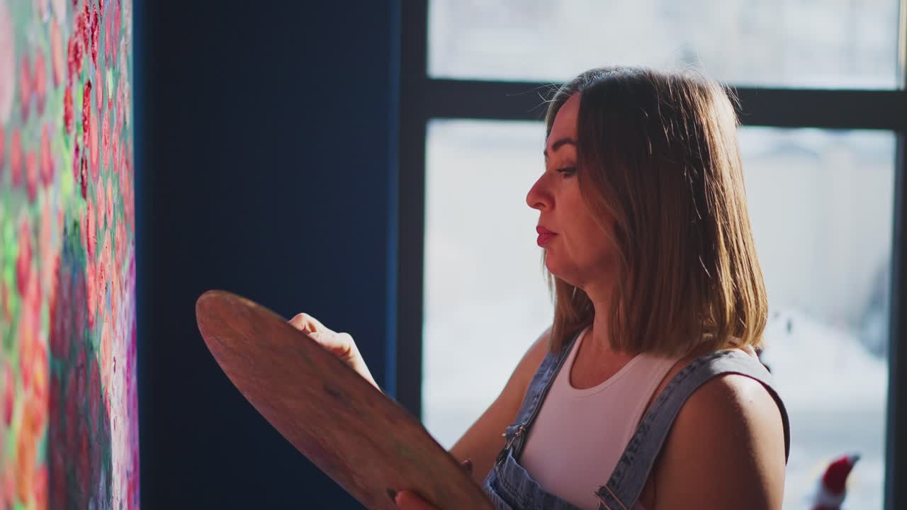 Artista donna che dipinge un'opera d'arte astratta su tela in studio