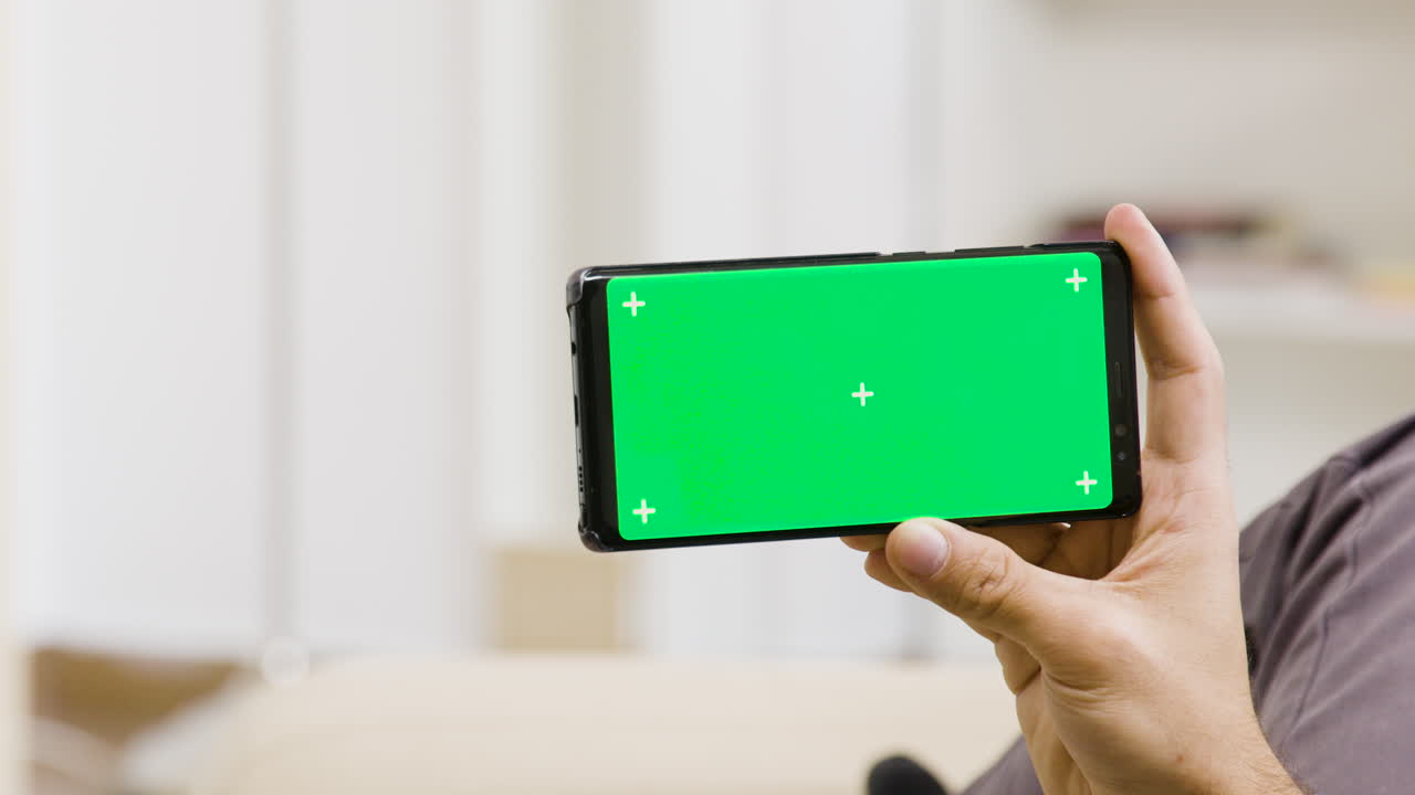 Smartphone with green screen held by a hand