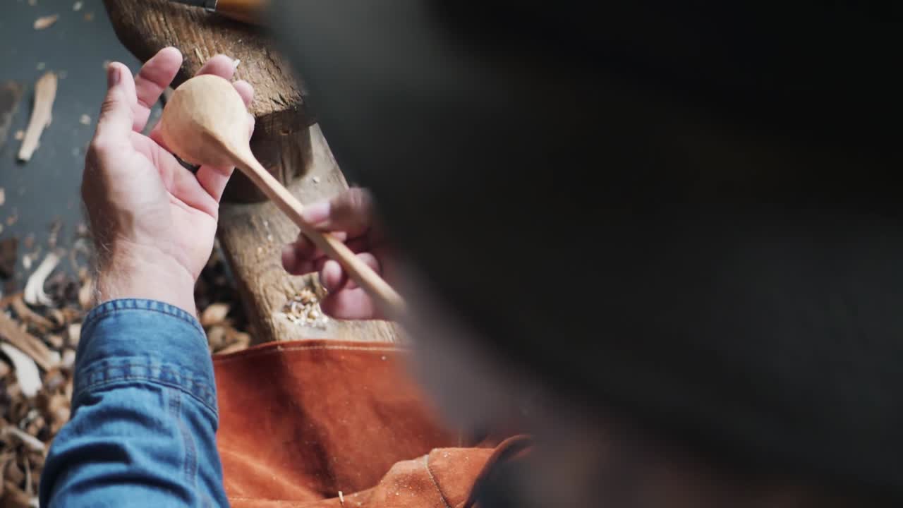 artesano de madera examinando una cuchara hecha a mano