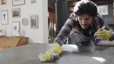 happy caucasian man cleaning worktop in kitchen, slow motion