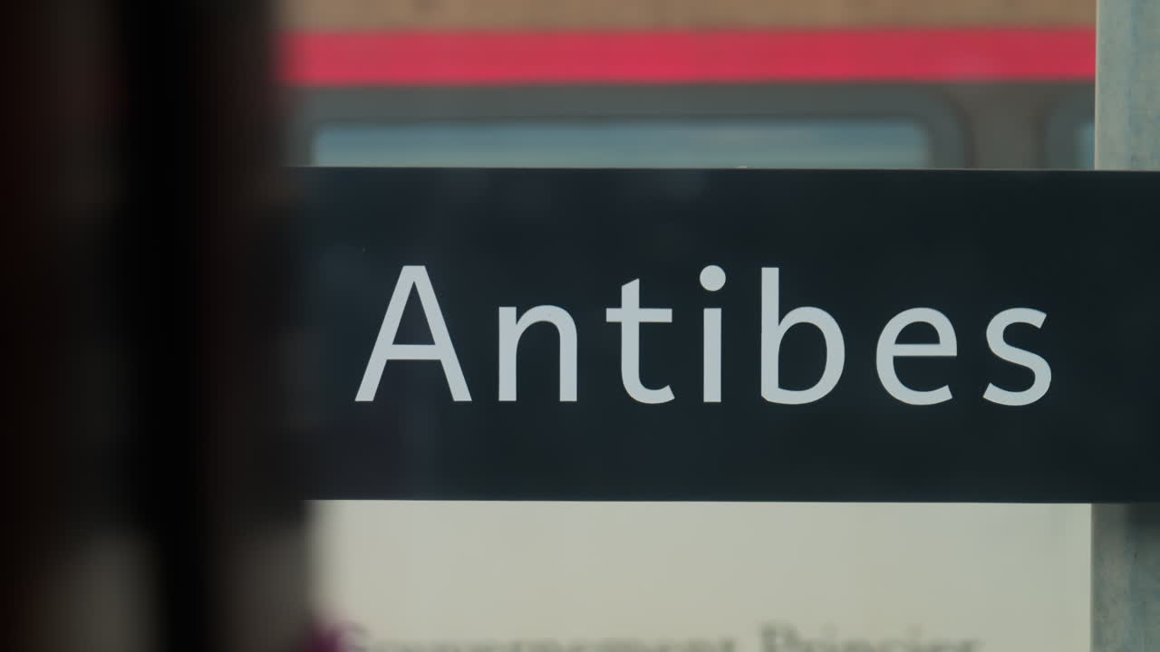 Antibes writing on a glass wall with a train moving on the background