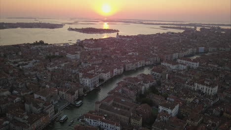 Toma-Aérea-Volando-Hacia-El-Amanecer-Y-El-área-De-Cannaregio-Sobre-El-Canal-Grande,-Venecia,-Italia