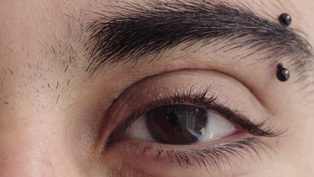 close up of hispanic man eye looking at camera wearing eyebrow piercing reflection vision eyesight