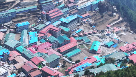 drone view of village en route to everest, traditional housings stretch from hill to valley under daylight, scenic and touristic mountain landscape aesthetics tradition architecture