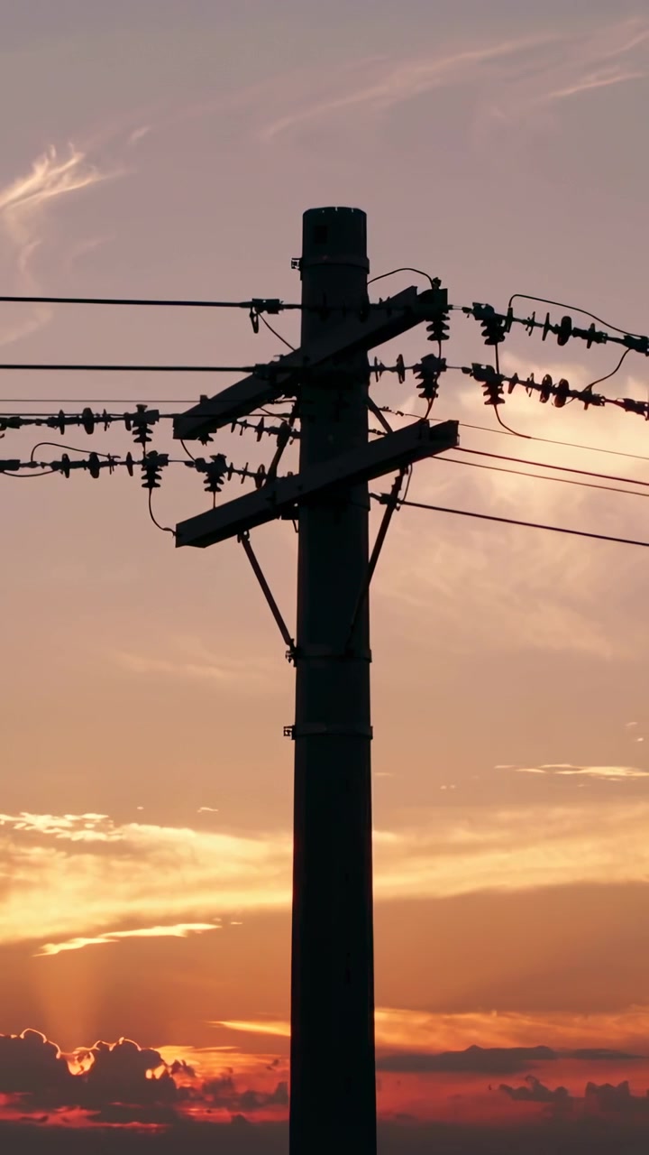 縦型動画: 移り変わる空の下、地平線の中央に電柱が固定され、腕金、電線、碍子が見える様子