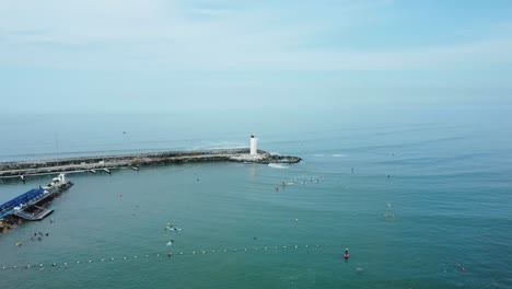 Small-white-lighthouse-at-the-end-of-a-rocky-pier