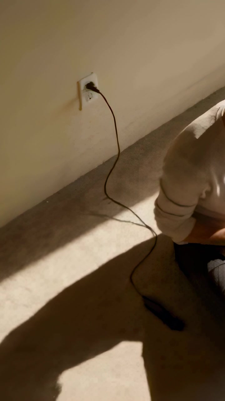 Vertical video: Shifting woman in ribbed top adjusting by outlet moving cable module, copy space