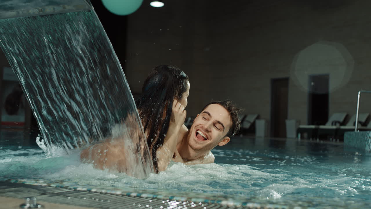 스파 수영장에서 웃기는 커플. 예쁜 남녀가 자쿠지에서  ⁇ 안고 있다.