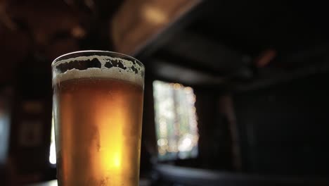 static shot of a cold beer in a pub with a fan in the background