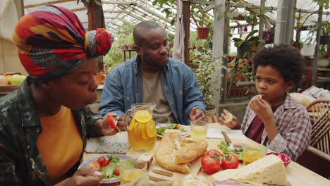 african american family enjoying dinner in greenhouse farm