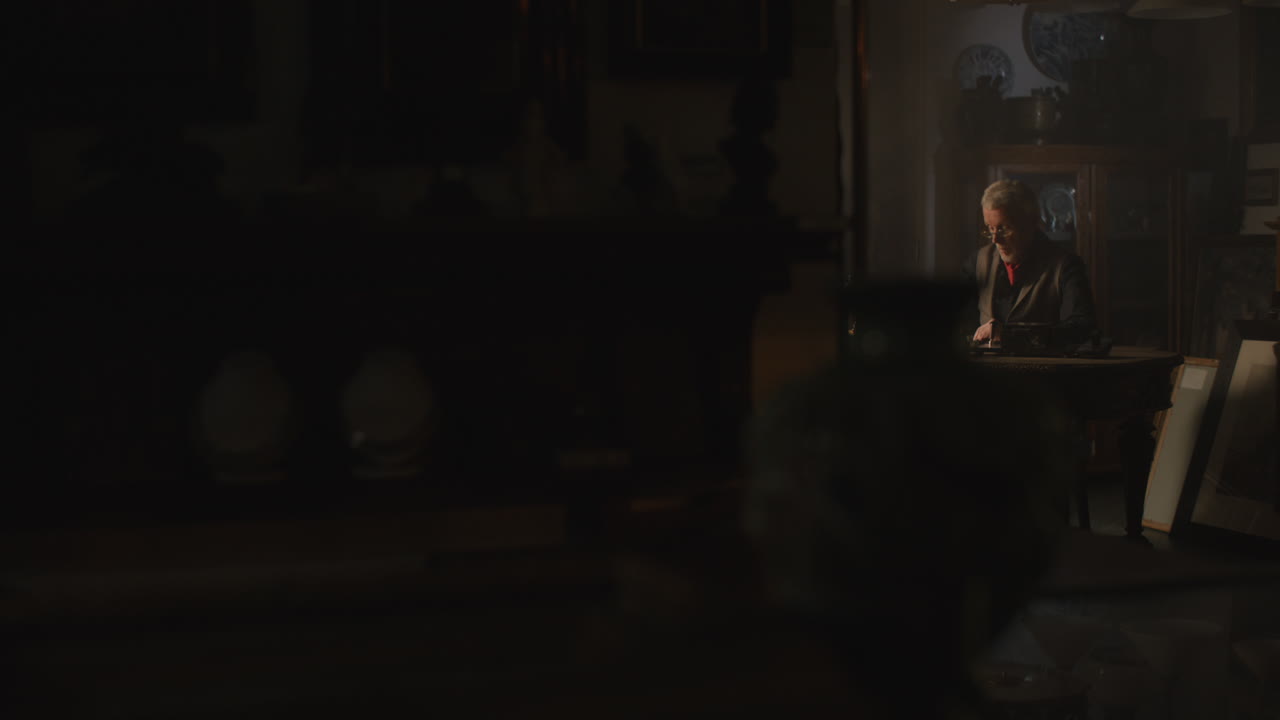 Old passionate man writes a letter in his office at night