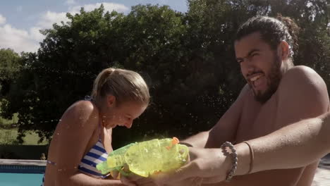 amigos jugando con una pistola de agua en la piscina