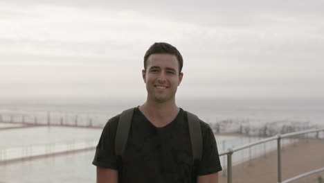 Retrato-De-Un-Joven-Atractivo-Sonriendo-Feliz-De-Pie-Bajo-La-Lluvia-En-La-Playa