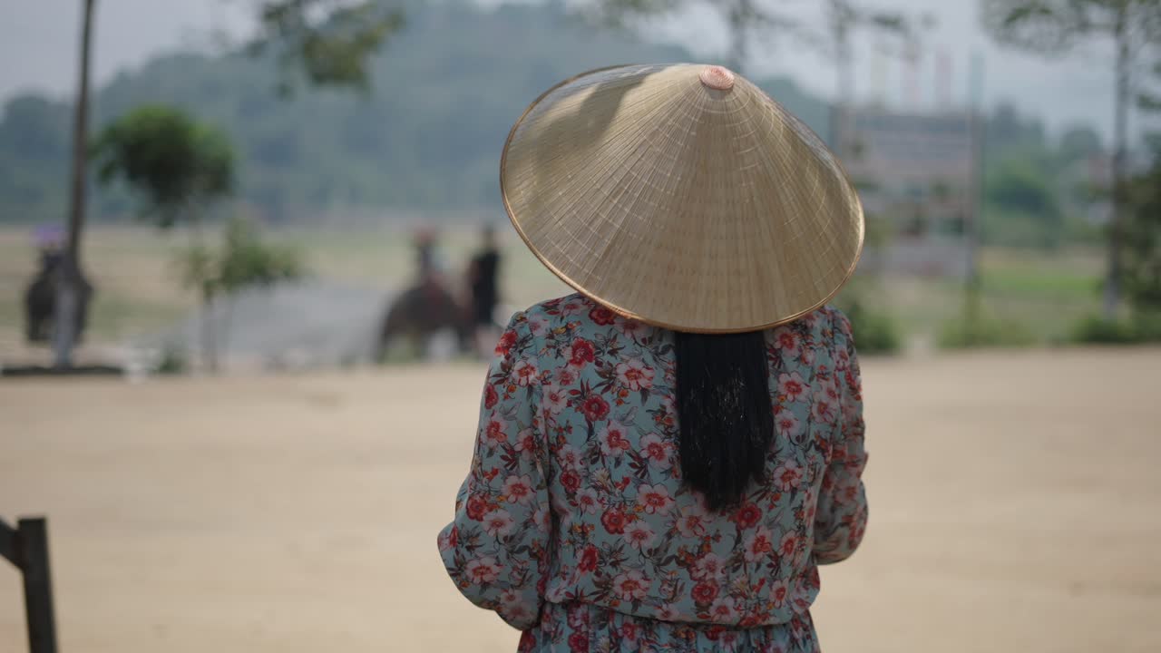 Vietnamese Woman Observing Elephant Riders in Rural Setting