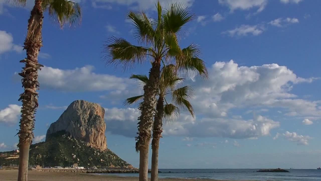 pina de ifac calpe con nubes flotando y olas rompiendo en la playa cálida tarde de verano
