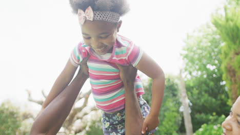 Glückliches-Afroamerikanisches-Paar-Mit-Ihrer-Tochter,-Die-Im-Garten-Spielt