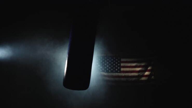 Un sacco da boxe ondeggia nella sala nella nebbia e sotto i riflettori sullo sfondo della bandiera statunitense, video 4K.