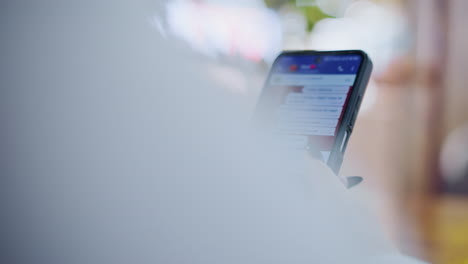 close-up of black cell phone being used for chatting on a wooden table, fingers typing on keyboard, screen displaying text messages, blurred light effects around