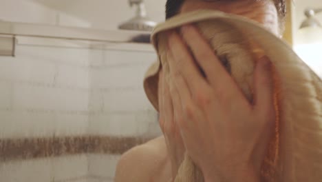 a young guy wiping towel inside the bathroom after bath