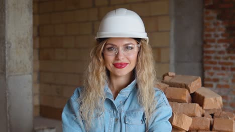 young woman in a work helmet and denim clothes wears glasses at the construction site. woman worker in construction industry