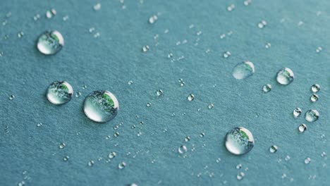 Micro-video-of-close-up-of-water-drops-with-copy-space-on-blue-background