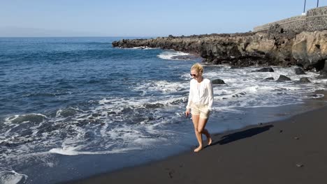 Kaukasische-Frau-Zu-Fuß-Am-Schwarzen-Sandstrand-Von-Teneriffa,-Kanarische-Inseln,-Spanien