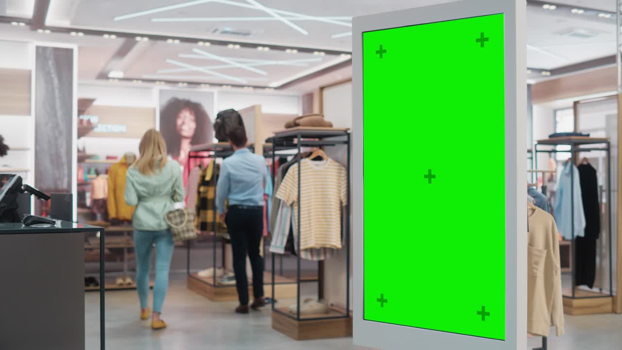 Customer Using Floor-Standing LCD Touch Display with Green Screen Chroma Key Mock Up while Shopping in Clothing Store. She is Checking for Information, Looking at a Floor Plan, Choosing Items Online.