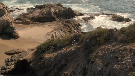 Bandada-De-Pájaros-Pelícanos-Anidando-En-La-Colina-Con-Olas-Rompiendo-En-La-Costa-Rocosa-De-El-Faro-De-Bucerias-En-Michoacán,-México