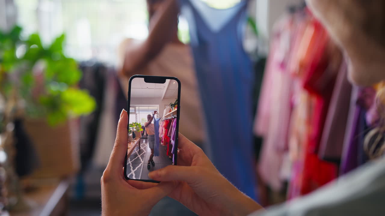 dos amigos comprando ropa en una tienda de moda tomando un video del vestido